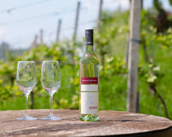 Weingut Grasmuck in Gamlitz, Südsteiermark - eine Flasche Cuvee von der Ried'n im Weingarten, daneben zwei Weingläser